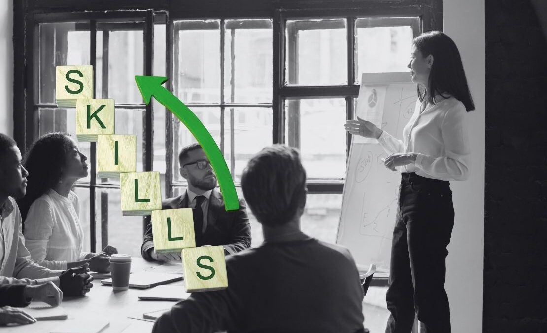 Trainer presenting to a team with visual aids and 'SKILLS' staircase graphic, representing top skills for effective training and professional growth